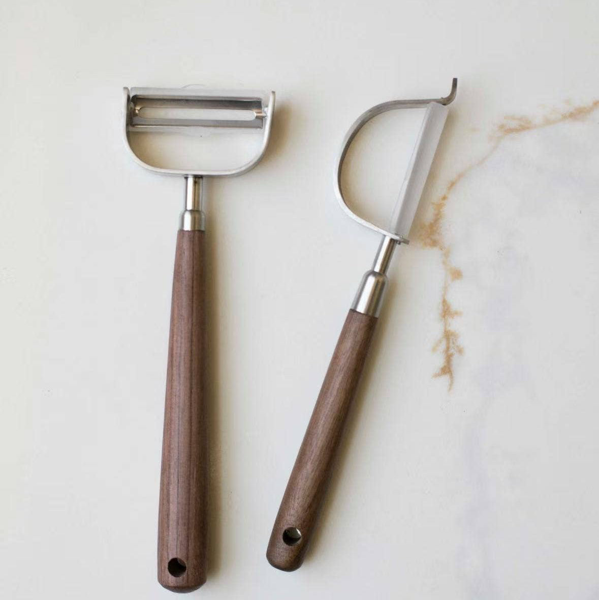 metal cheese graters with wooden handles on a marble surface